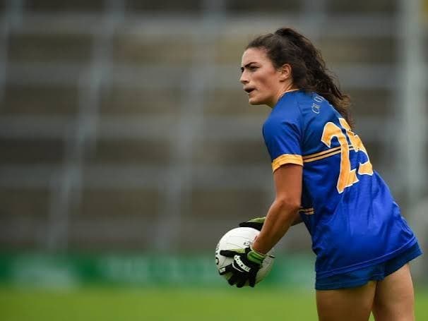 Lucy Rock in Wicklow colours, ball in both hands, between plays